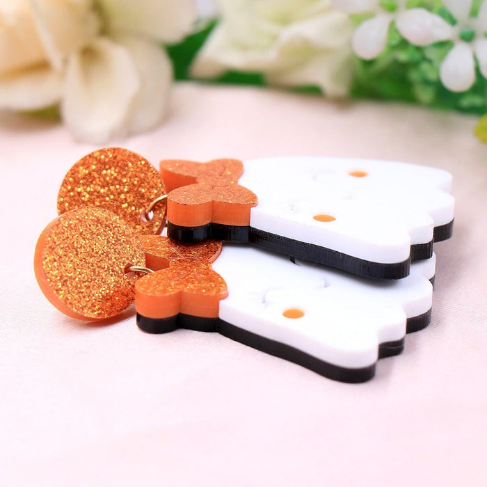 Glitter orange ghost face drop earrings with white backing and black hooks, pair on display
