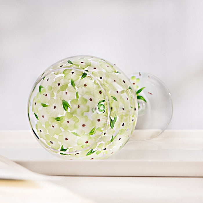 Clear stemmed glass with green leaf-and-vine pattern and small pink dots on bowl