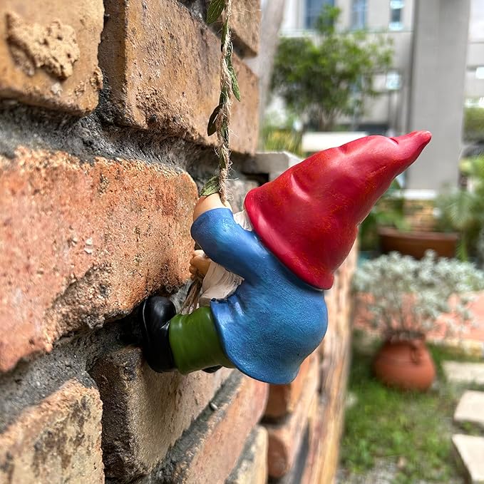 Climbing gnome ornament on rope along brick wall, red hat, blue body, white beard, green pants