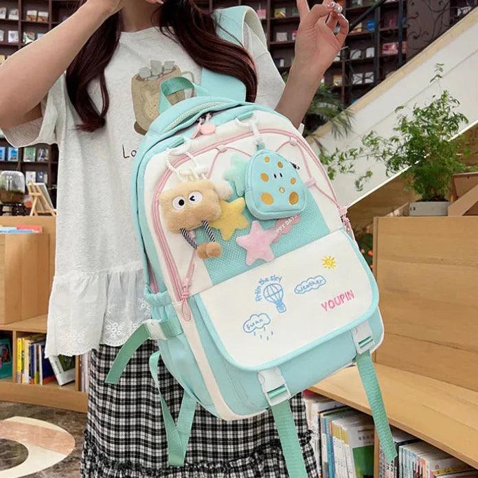 Light teal cartoon backpack with star and character patch, front pocket, and adjustable straps.