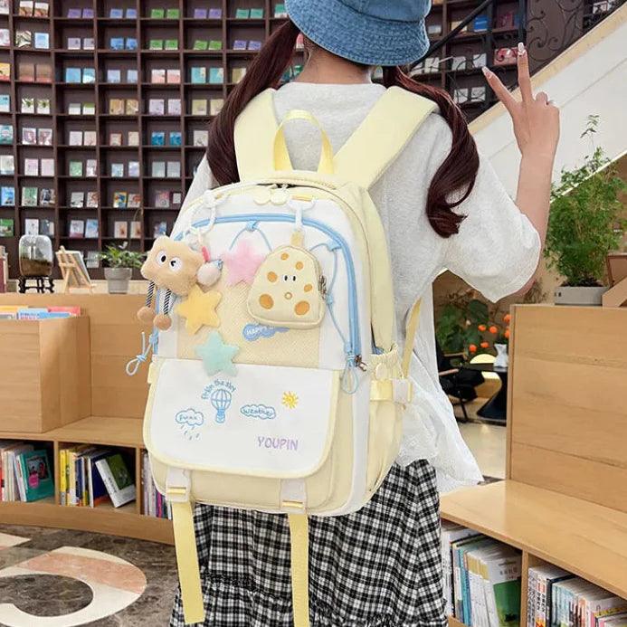 Light yellow and white cartoon backpack with star charm, front flap pocket, and straps.