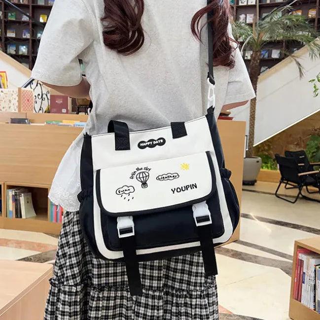 Black-and-white crossbody bag with flap front pocket and adjustable shoulder strap.