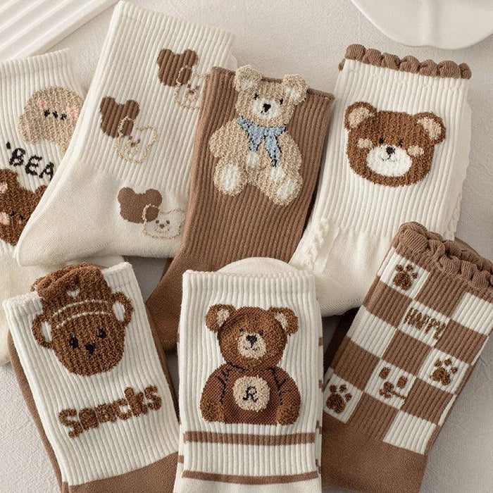 Assorted teddy bear socks bundle in white and brown, featuring stitched bear faces and striped legs.