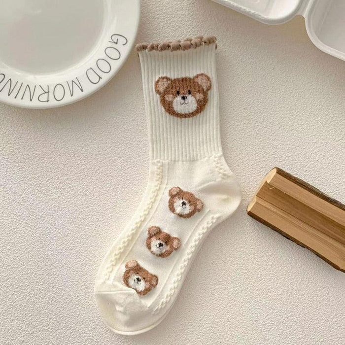 White teddy bear socks with brown bear faces and hearts on the cuffs and shaft.
