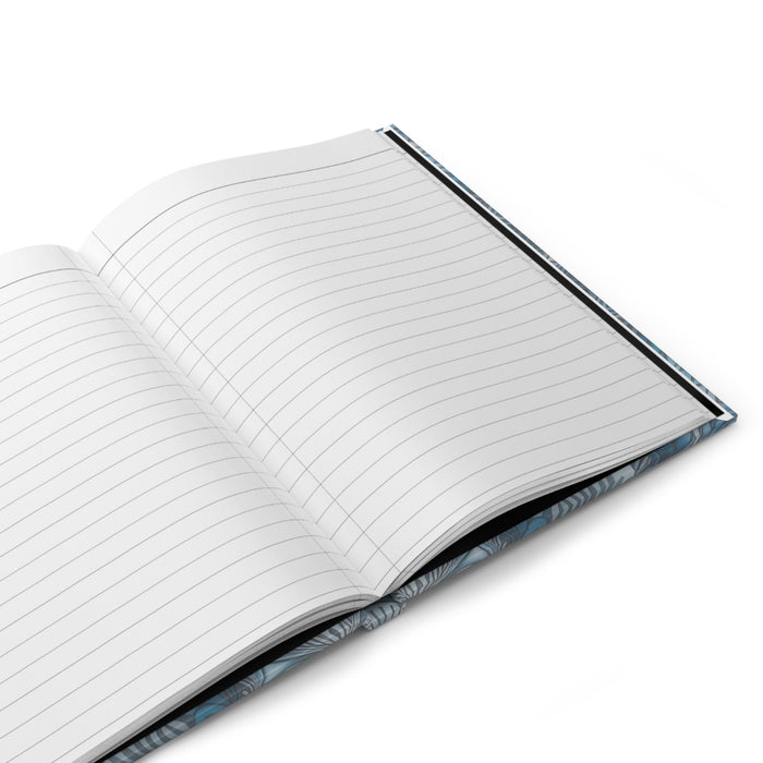 Matte hardcover journal opened to lined pages with blue patterned edge