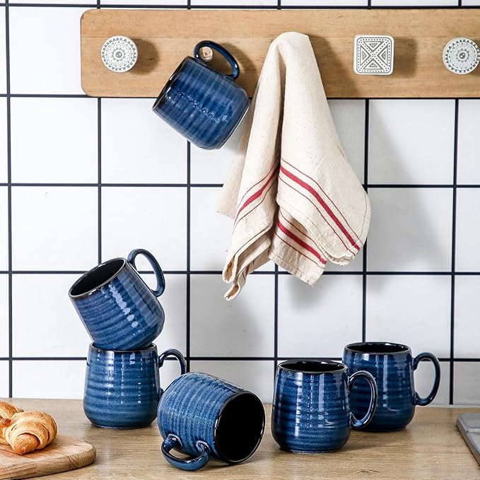 Blue ceramic espresso mugs with handles and black interiors on a tiled counter