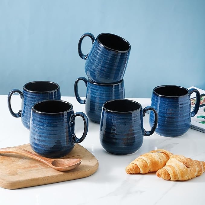 Blue ceramic espresso cups set with black interiors and side handles on wooden tray