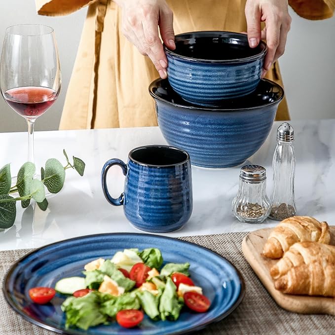 Blue ceramic espresso cups with black interiors, stacked by hands on table
