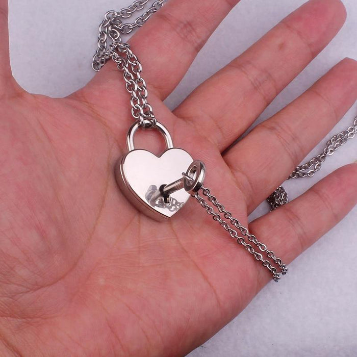 Heart locket necklace close-up with key inside and chain links, silver tone