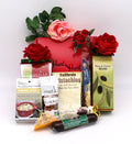 Red gift box filled with snack packages and red and pink roses, mint leaves