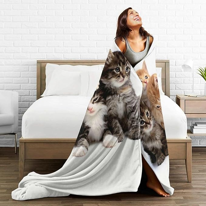 Cats throw blanket draped on a bed, white fleece with a group of kittens print