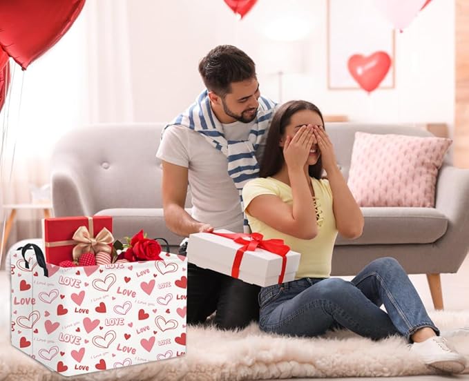 Pink heart Love gift basket with black handles holding a red ribbon-wrapped present
