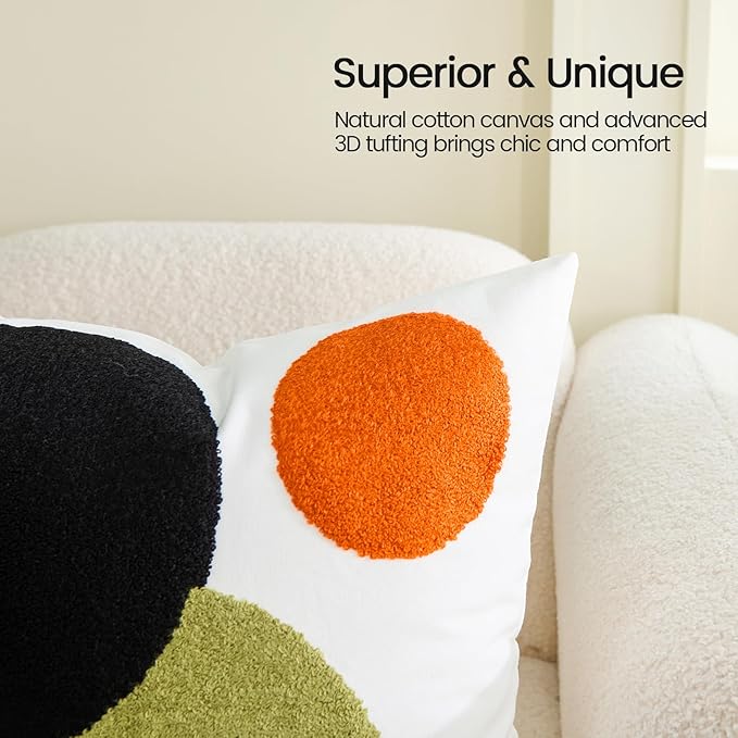 White pillow cover with tufted orange circle patch over black and olive-green abstract shapes