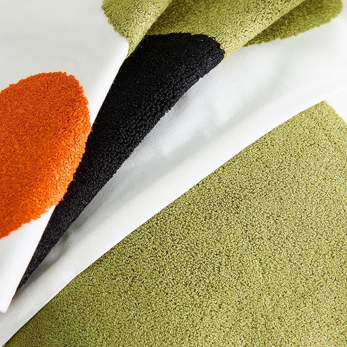 Close-up of tufted pillow cover fabric showing olive-green, black, and orange circle patches
