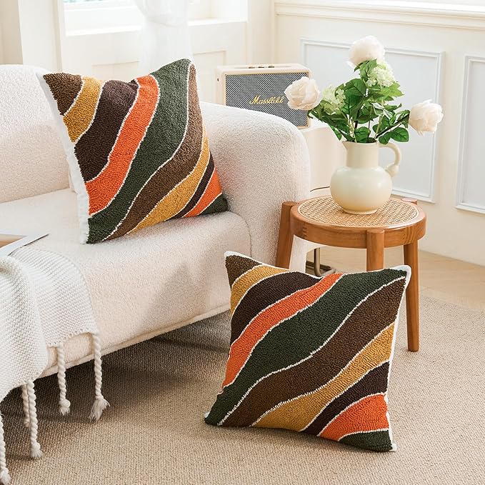 Tufted square pillow cover with curved striped bands in dark green, brown, orange, and tan