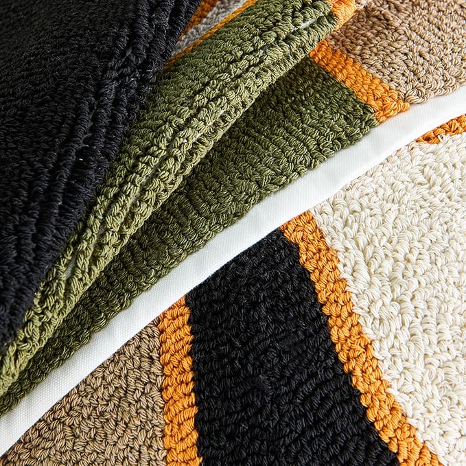 Tufted fabric close-up: olive and black grid cross with orange trim on beige base