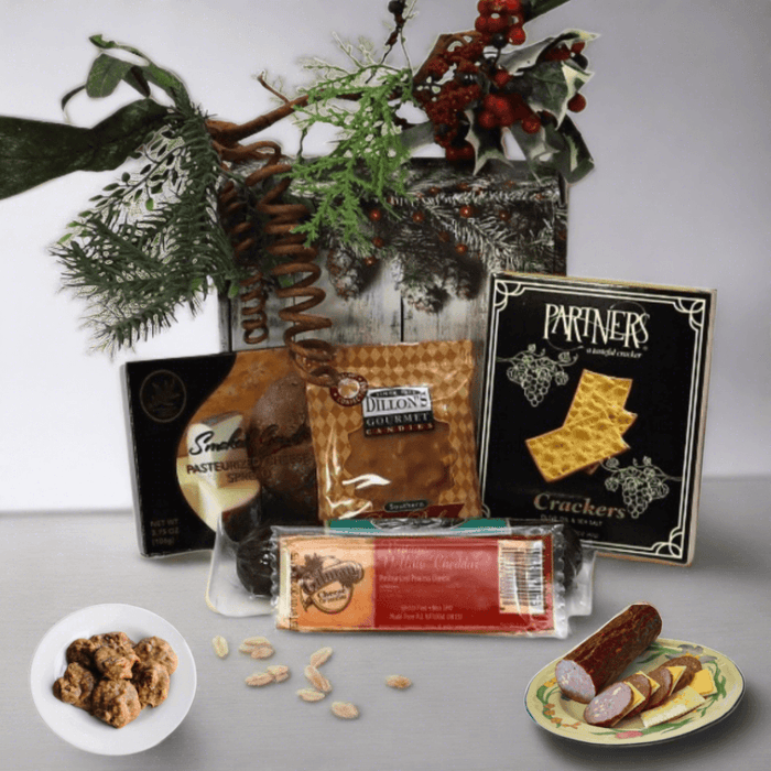 Holiday gift box with assorted snack packages and pine decor, open tray view