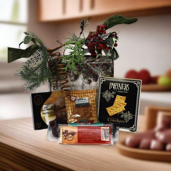 Holiday gift box with pine and berry ornament, wrapped treats on a table