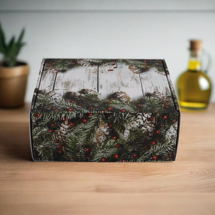 Holiday gift box with evergreen and berry design on the lid, closed on a table