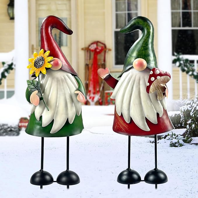 Two outdoor metal gnome statues with green and red hats, white beard, black stake feet