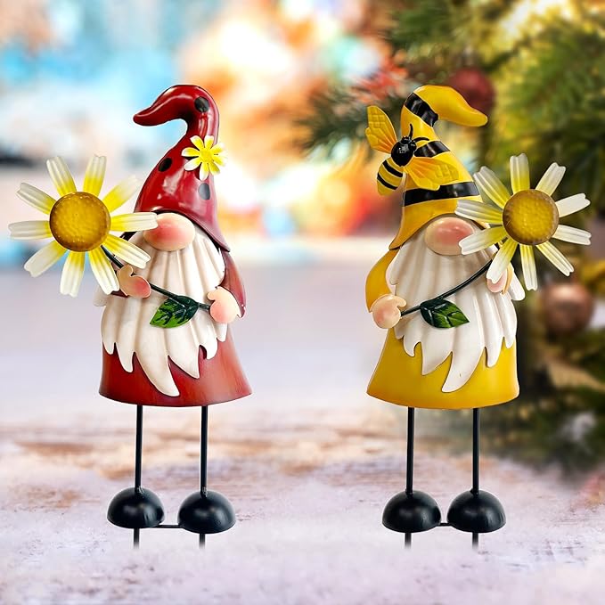 Two standing metal gnome statues: ladybug red and bee yellow, each with daisy flowers