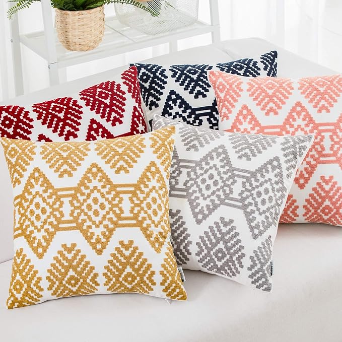 Geometric throw pillow set with orange embroidered cover among multicolor pillows