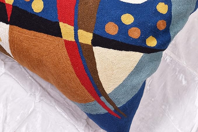 Close-up of blue abstract pillow cover with brown panel, red stripe, and yellow circles