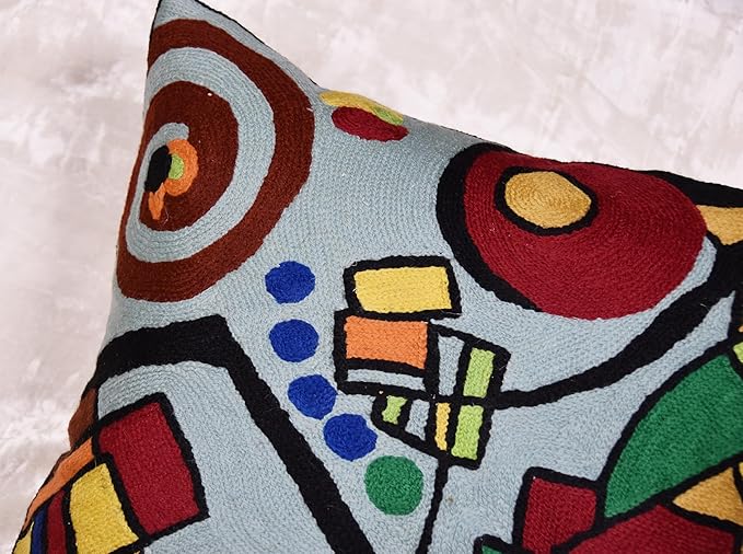 Close-up embroidered abstract geometric pillow cover with red, yellow, green, blue shapes