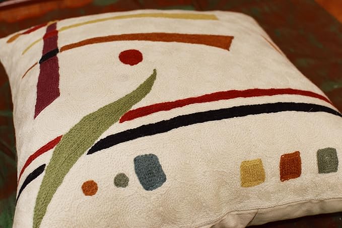 Cream abstract pillow cover close-up with green leaf shape and colored block dots