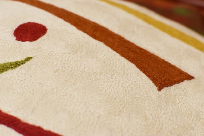 Cream pillow cover close-up with rust orange stripes and small red dot