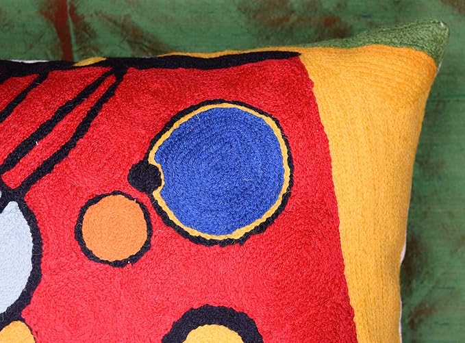 Close-up of red abstract embroidered pillow cover with a blue oval and orange dots