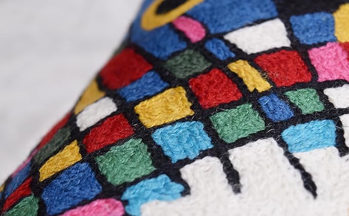 Close-up of black abstract embroidered pillow cover stitching with colorful grid pattern.