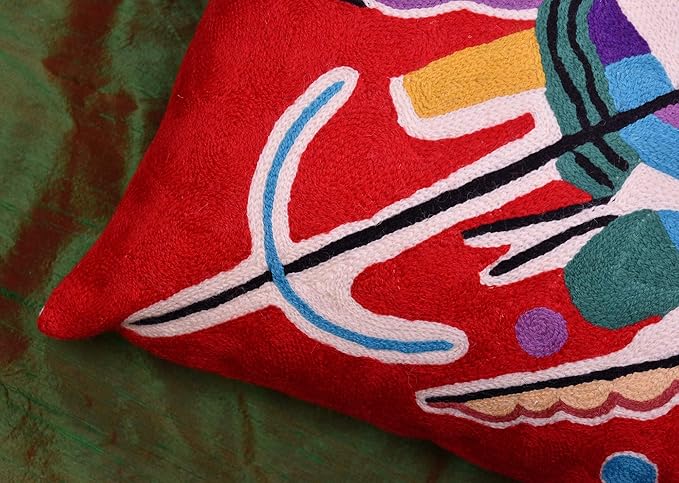 Red abstract pillow cover corner with curved blue line and colorful geometric motifs