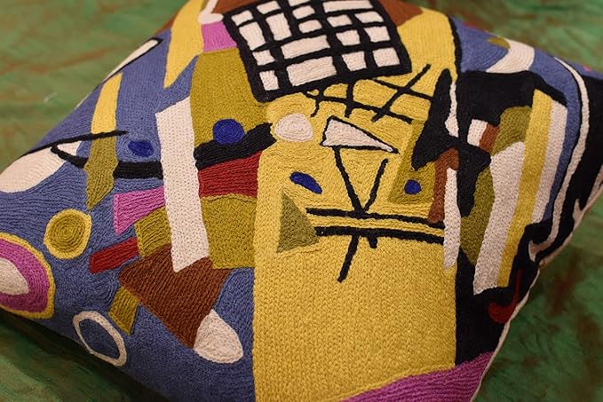 Abstract embroidered pillow cover detail with yellow shapes and black grid blocks