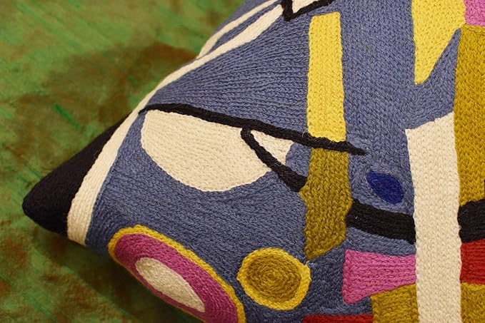 Abstract embroidered pillow cover corner with blue, yellow, and pink geometric shapes