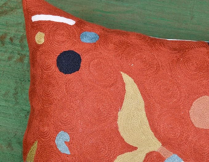 Orange abstract pillow cover with large beige leaf-like form and small blue dots