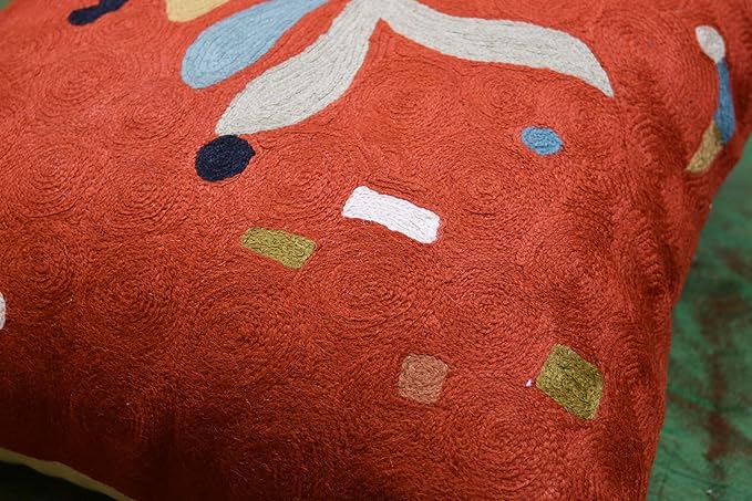 Orange abstract pillow cover with white rectangle and scattered green and blue accents