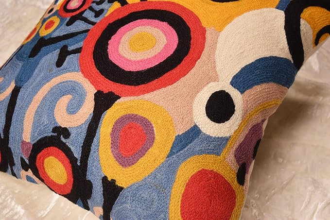 Embroidered decorative pillow cover with swirling motifs and circular patterns in bright blue, yellow, and red.