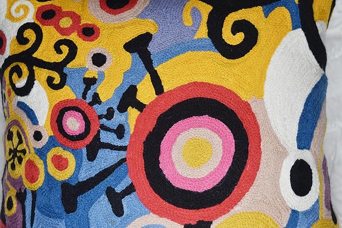 Front view close-up of embroidered pillow cover with circular ring motif in pink and black on blue.