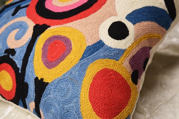 Pillow cover side detail with embroidered circles and small dots in cream, blue, yellow, and red.