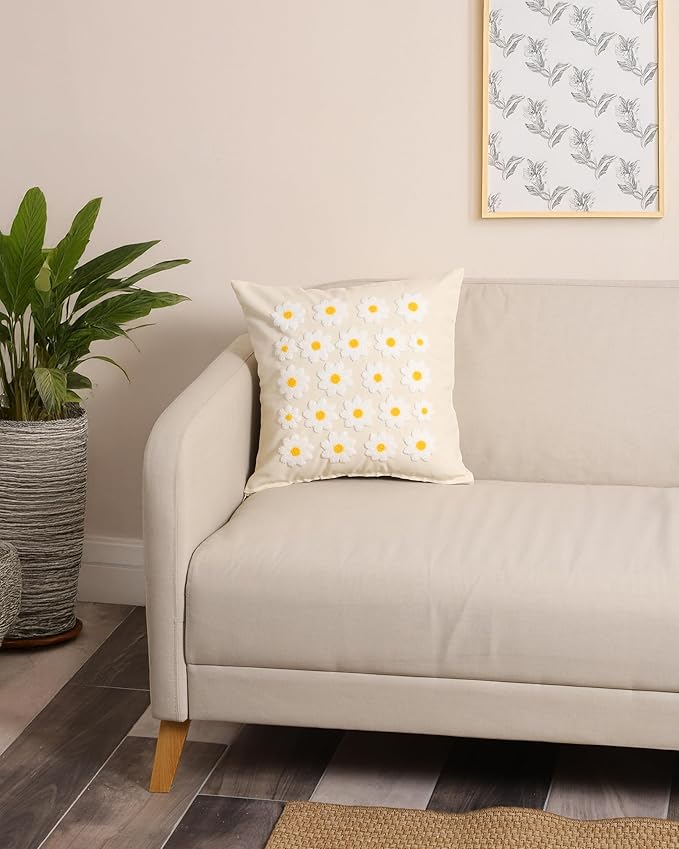 Daisy throw pillow cover on sofa, white fabric with yellow flower centers and textured stitching