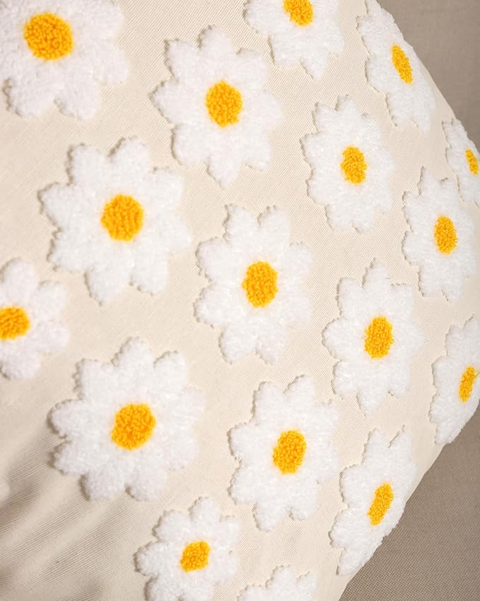Close-up daisy stitching on cream pillow cover, white flowers with yellow centers