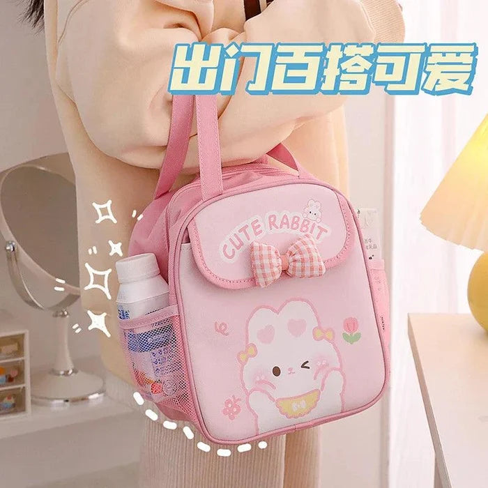 Pink insulated animal lunch bag being carried, with bow front pocket and bunny illustration