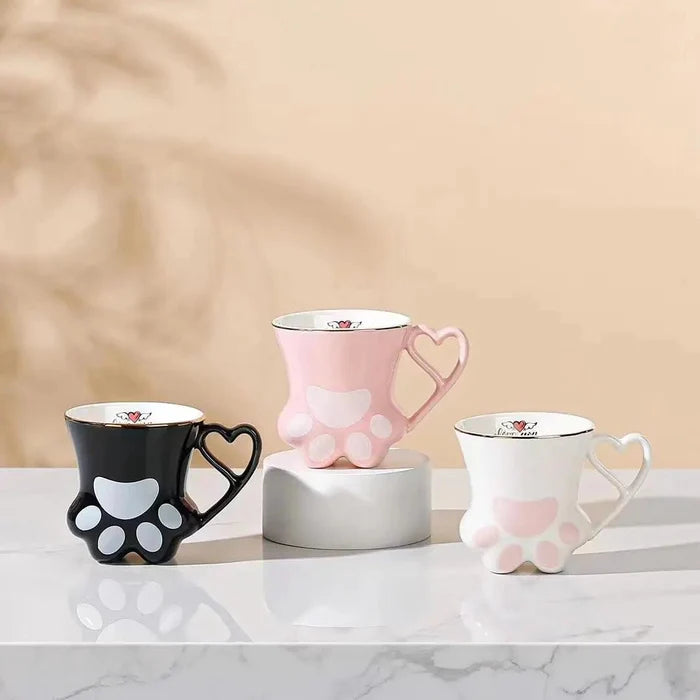 Set of cat paw mugs in black, pink, and white with heart handles and paw pad designs