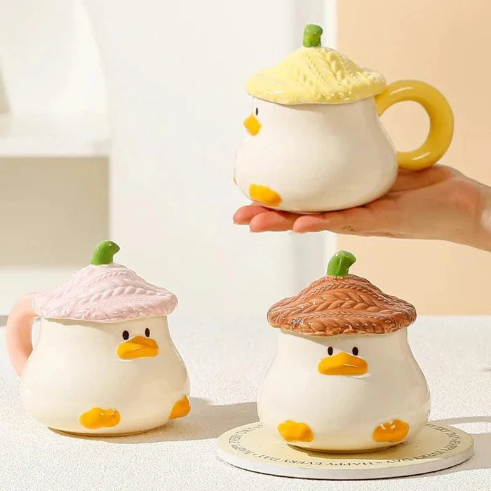 Duck-shaped ceramic mug with yellow textured lid and handle, orange beak and small webbed feet