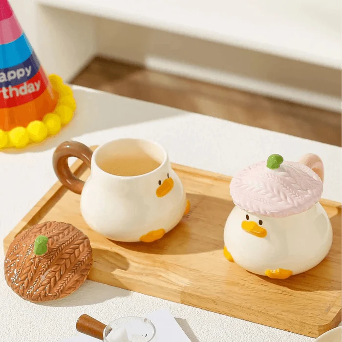 Duck-shaped ceramic mug with brown textured lid and side handle, with orange beak details