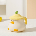 Duck-shaped ceramic mug with green textured lid, orange beak face, and side handle