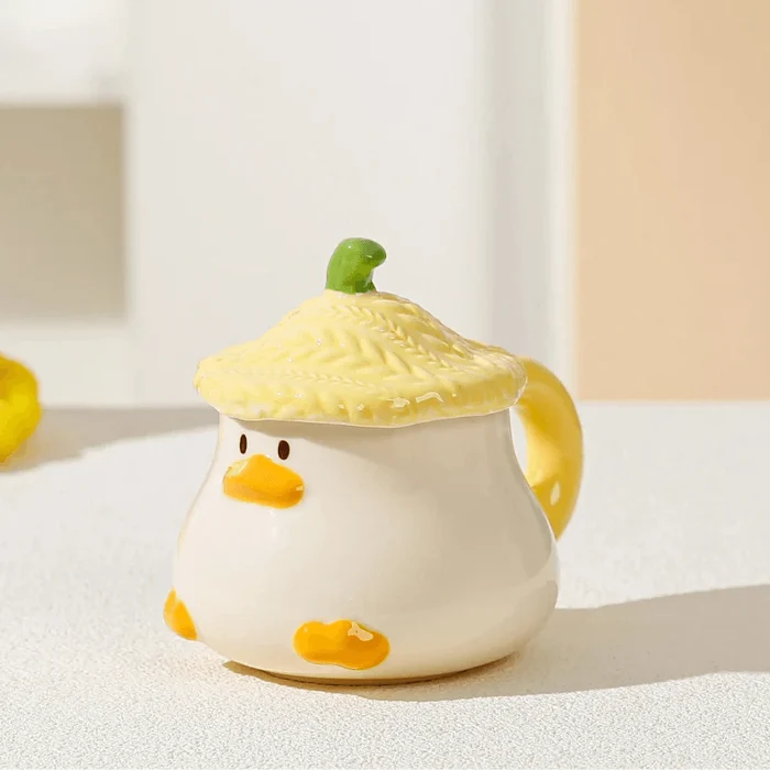 Duck-shaped ceramic mug with green textured lid, orange beak face, and side handle