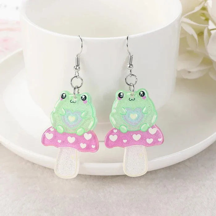 Pink-and-green frog face acrylic dangle earrings with heart motifs and tiny drops