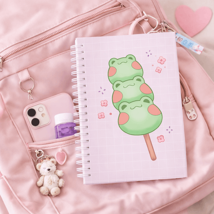 Square spiral notebook with lilac grid cover and green frog dango graphic with stick